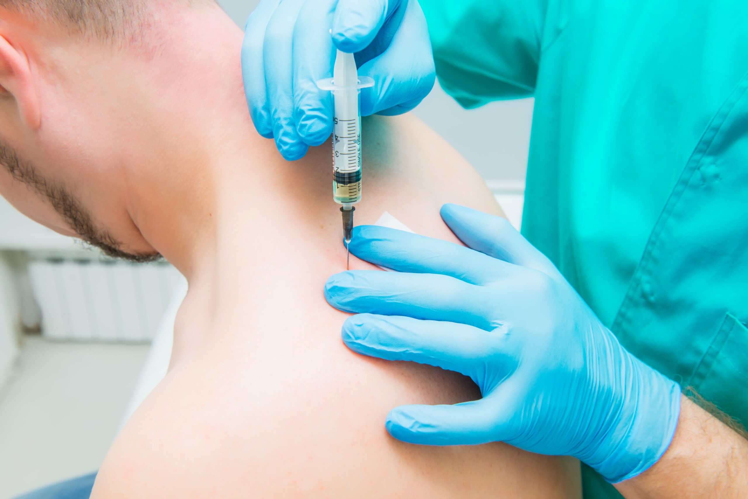 A clinician in gloves giving a trigger point injection in the upper back